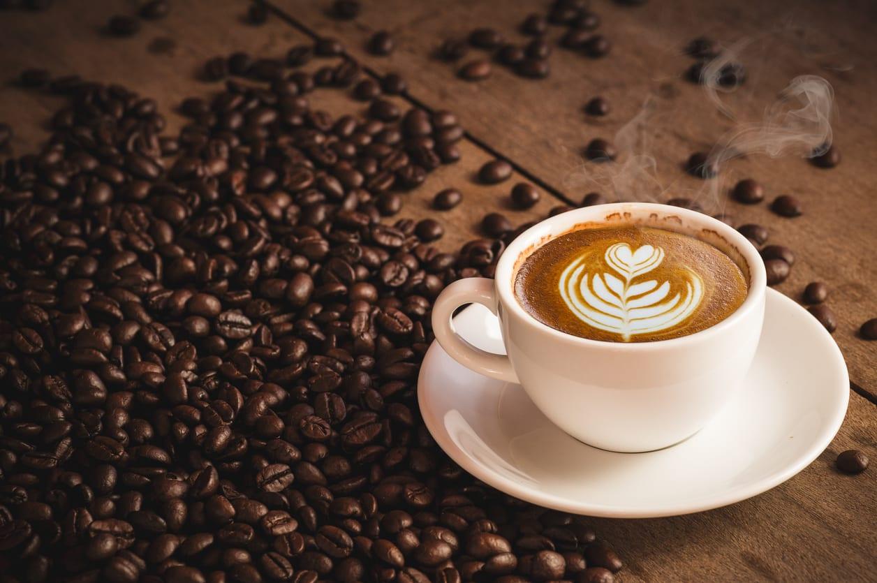 Coffee beans and Hot Cofee cup with latte art on wooden background. side view with copy space for your text