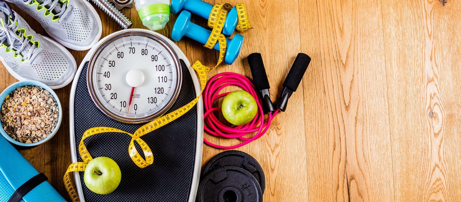 Sports and workout equipment on a wooden floor with healthy snacks, weight loss and physical activity concept