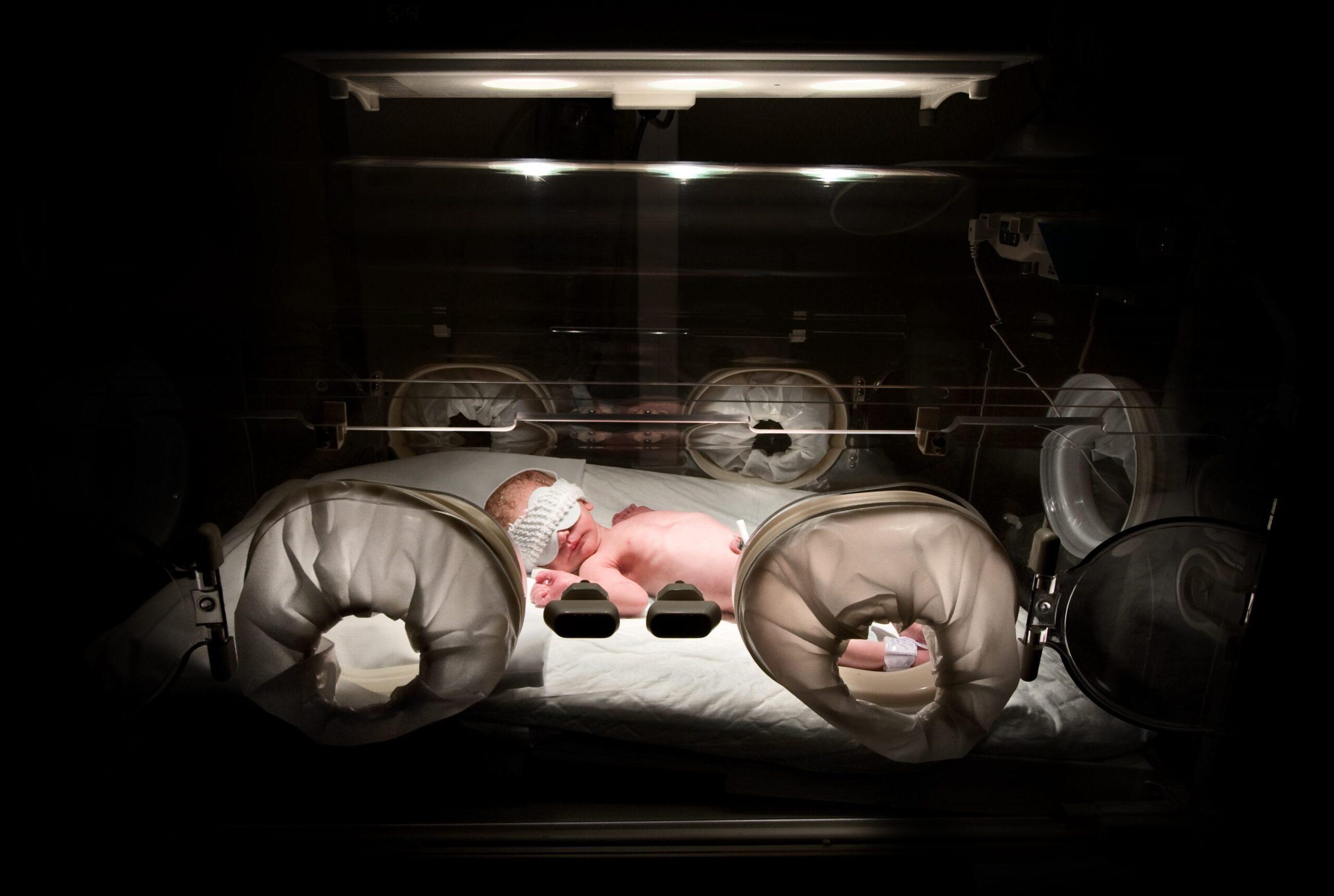 Newborn in incubator, low key